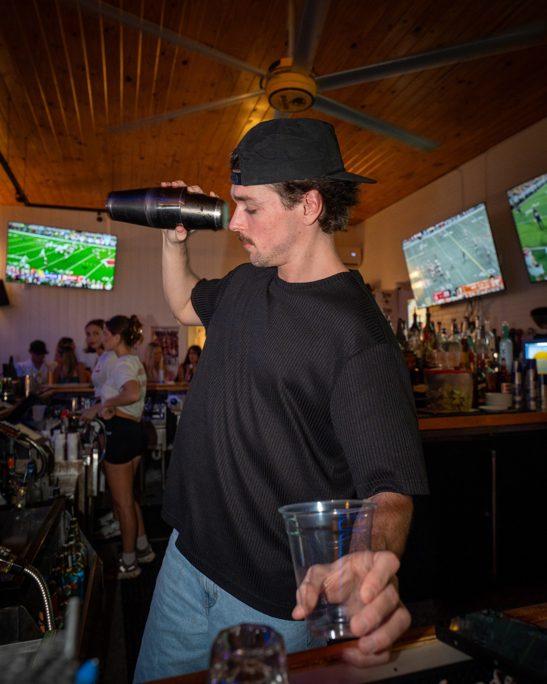 A bartender shaking a cocktail while holding a glass behind The Standard’s bar