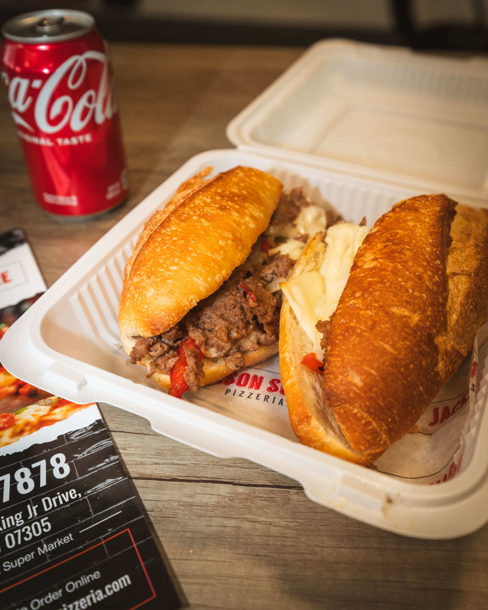 A hot sandwich filled with meat and melted cheese on Jackson Square branded paper