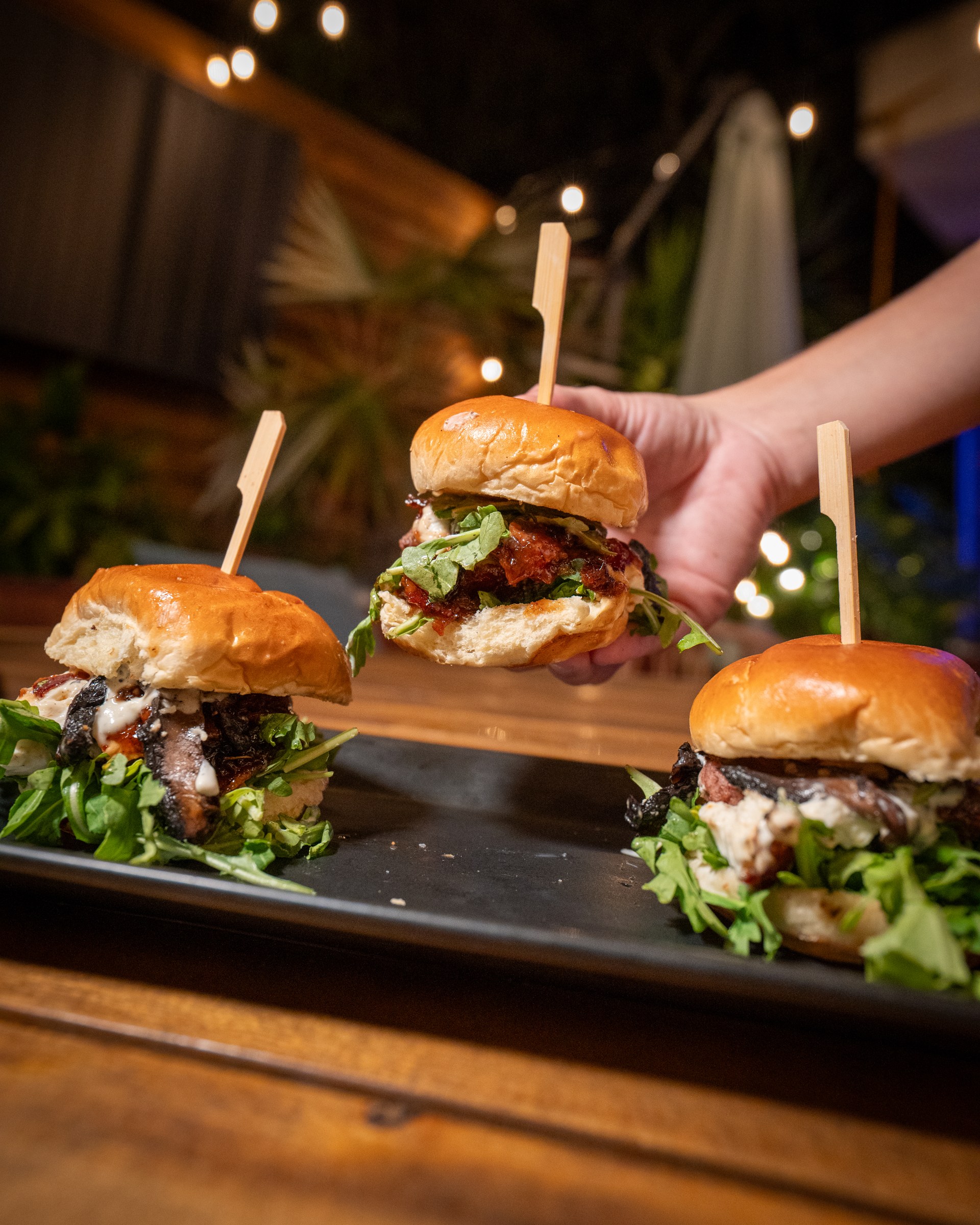 A hand lifting a slider from a tray at The Standard