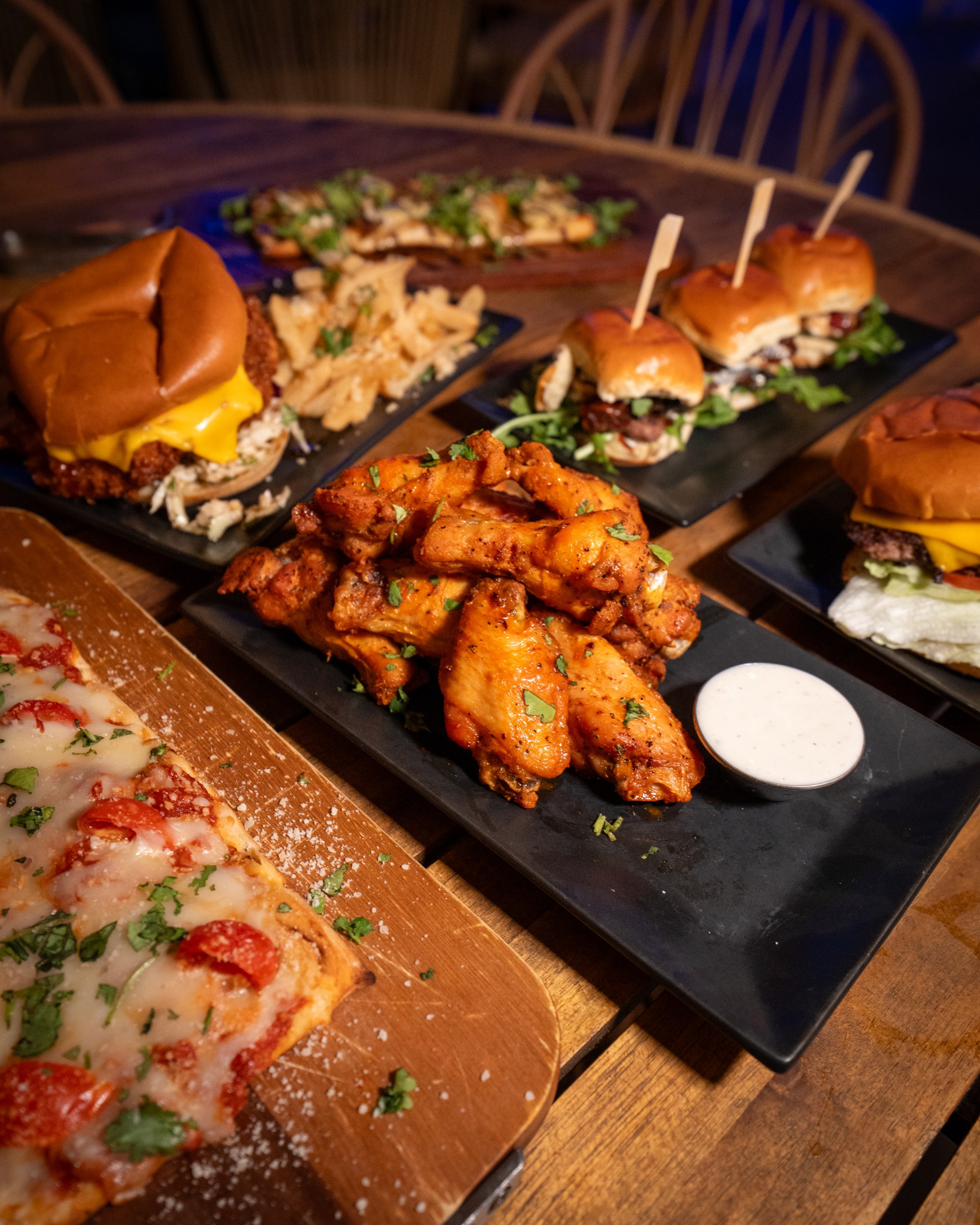 Pizza, wings, sliders, and fries spread across a table at The Standard Delray Beach