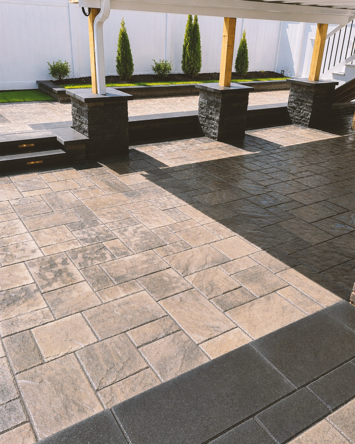 Patterned paver terrace and masonry steps leading to a covered porch